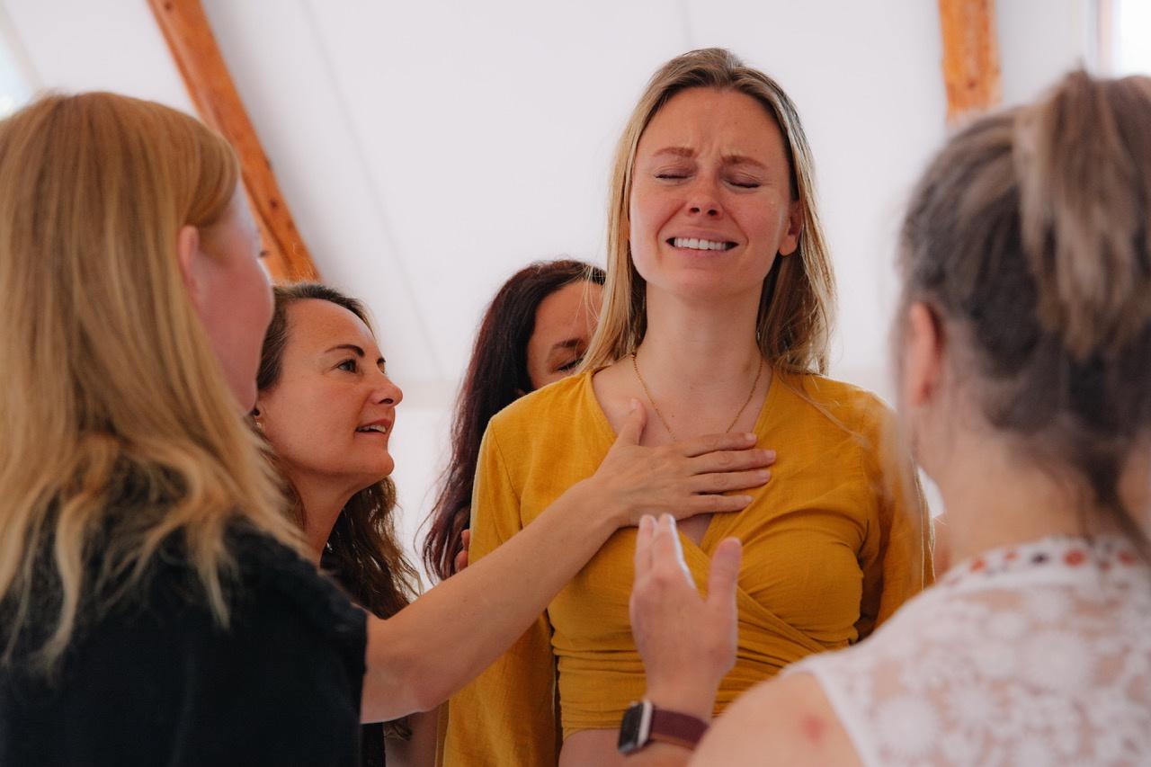 Women supporting a woman with a hand on her heart during Feminine Alchemy