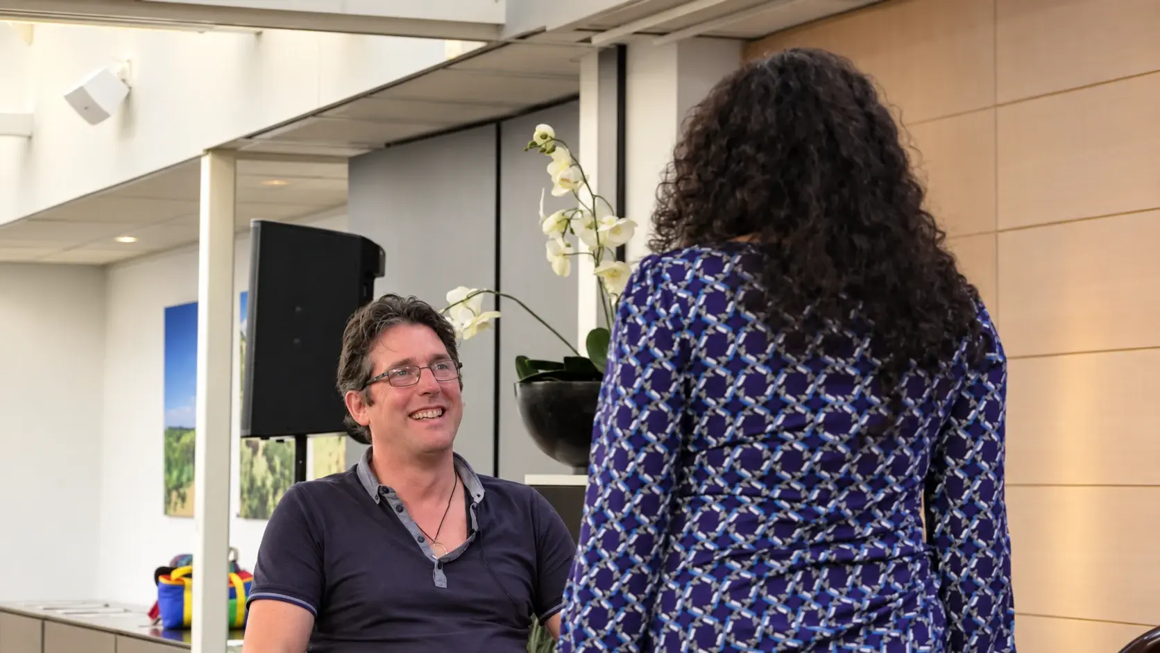 A seated partner smiling towards his standing partner