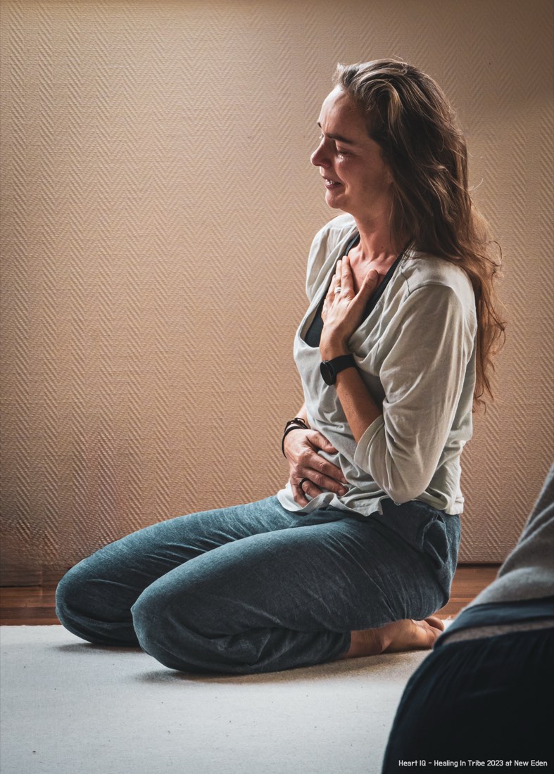A participant kneeling with a hand on her heart at Healing in Tribe, New Eden